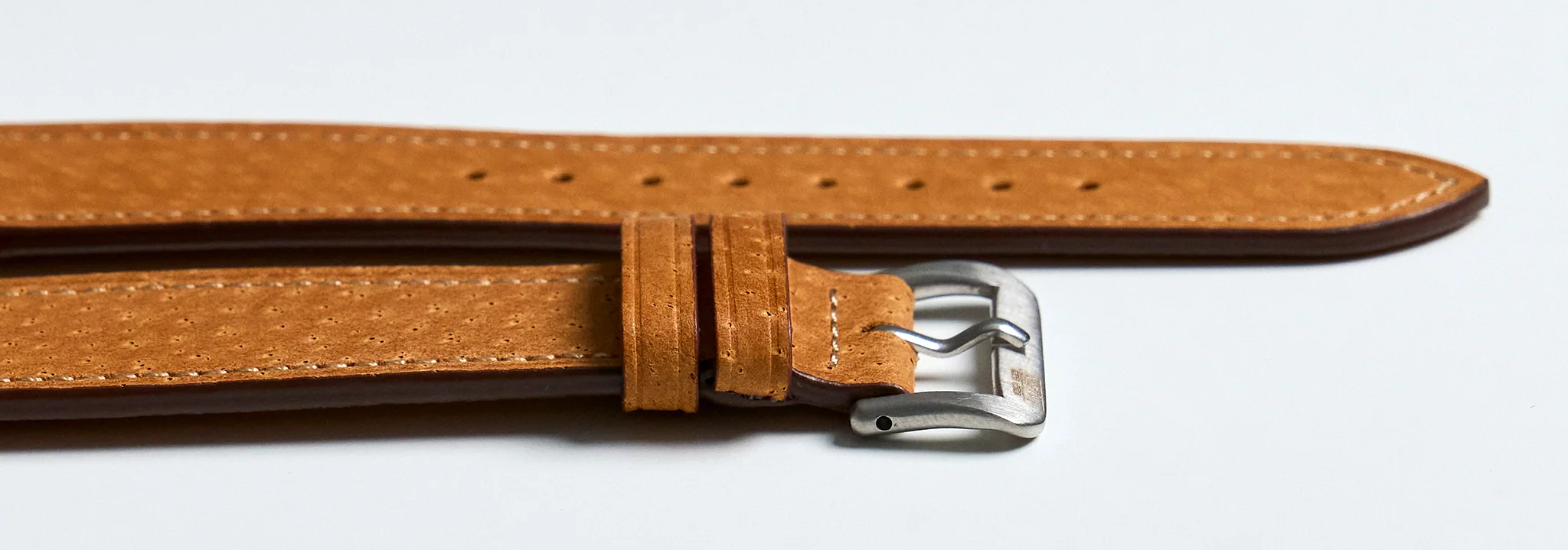 Side profile of a thin unpadded pigskin watch strap showing pore grain and edge thickness